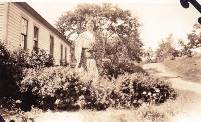 Marjorie in from of farm house on Oak Hill